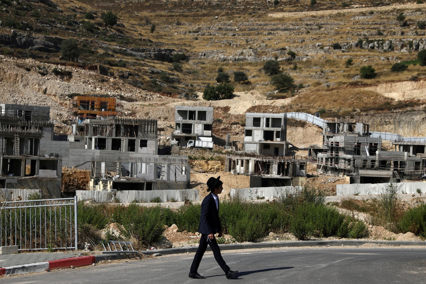 A Jewish settler walks past Israeli settlement construction sites in the Israeli-occupied West Bank near Jerusalem on June 30. (Ammar Awad/Reuters)