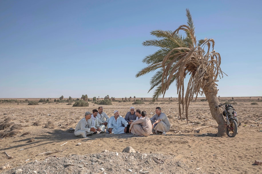 55-year-old Egyptian farmer Makhluf Abu Kassem, center, sits with farmers under shade of a dried up palm tree surrounded by barren wasteland that was once fertile and green, in Second Village, Qouta town, Fayoum, Egypt, Wednesday, Aug. 5, 2020. Abu Kassem fears that a dam Ethiopia is building on the Blue Nile, the Nile’s main tributary, could add to the severe water shortages already hitting his village if no deal is struck to ensure a continued flow of water. “The dam means our death,” he said. (Nariman El-Mofty/Associated Press)
