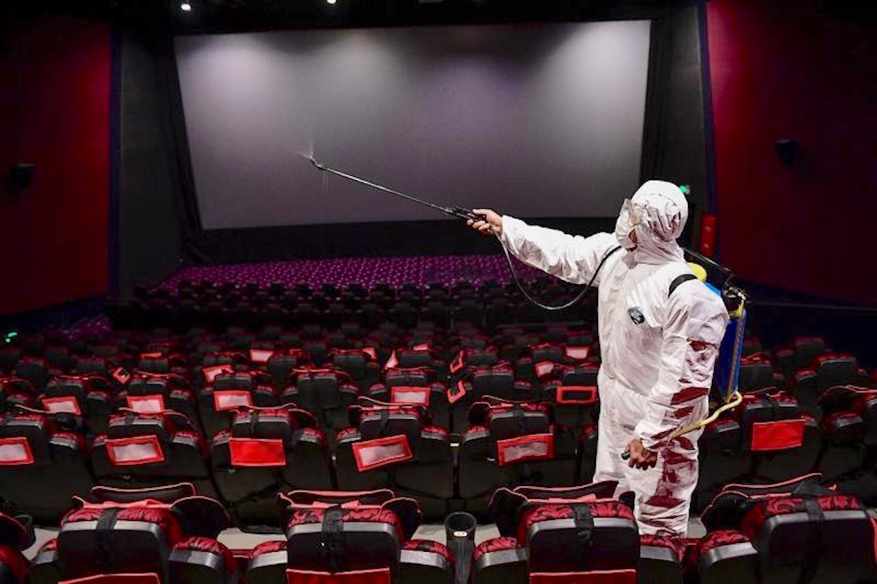 This photo taken on March 25, 2020 shows a staff member spraying disinfectant at a cinema as it prepares to reopen to the public after closing due to the COVID-19, in Shenyang in China's Liaoning province. (PHOTO/AFP)
