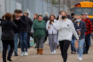 Parents walk away with their kids from the Meijer's parking lot in Oxford where many students gathered following an active shooter situation at Oxford High School in Oxford, Mich., Nov. 30, 2021. (Image Eric Seals/Detroit Free Press via USA Today Network)