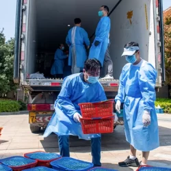 Community volunteers deliver vegetables to be distributed to residents in a compound during a Covid-19 lockdown in Shanghai on April 12, 2022. (Image: Liu Jin/Getty).