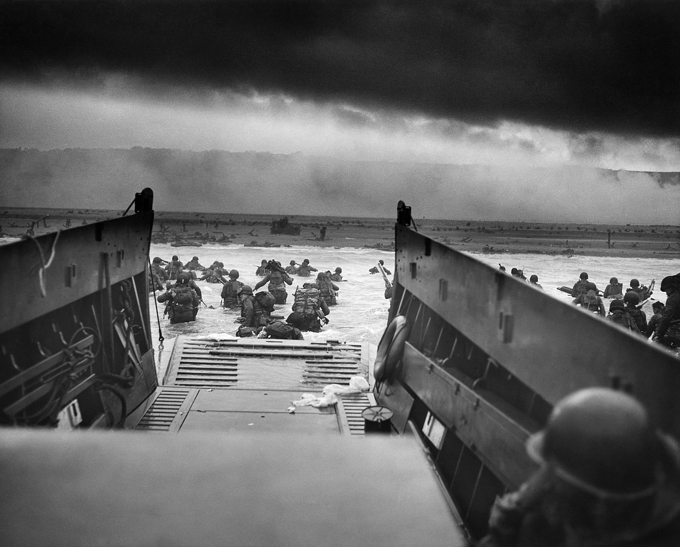 A LCVP (Landing Craft, Vehicle, Personnel) from the U.S. Coast Guard-manned USS Samuel Chase disembarks troops of Company A, 16th Infantry, 1st Infantry Division (the Big Red One) wading onto the Fox Green section of Omaha Beach (Calvados, Basse-Normandie, France) on the morning of June 6, 1944. American soldiers encountered the newly formed German 352nd Division when landing. During the initial landing two-thirds of Company E became casualties.