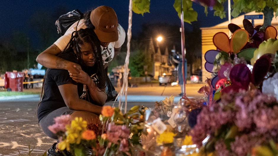 Two women at a memorial honoring the victims of the Tops shooting across the street from the store in Buffalo (Image by The Washington Post/Getty Images)